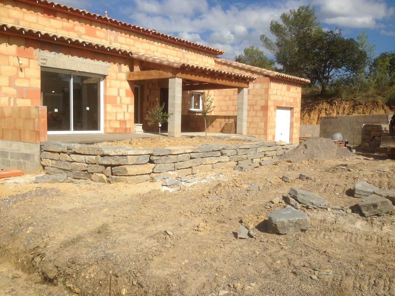 Mur en pierres au pied de la terrasse d’une maison en construction