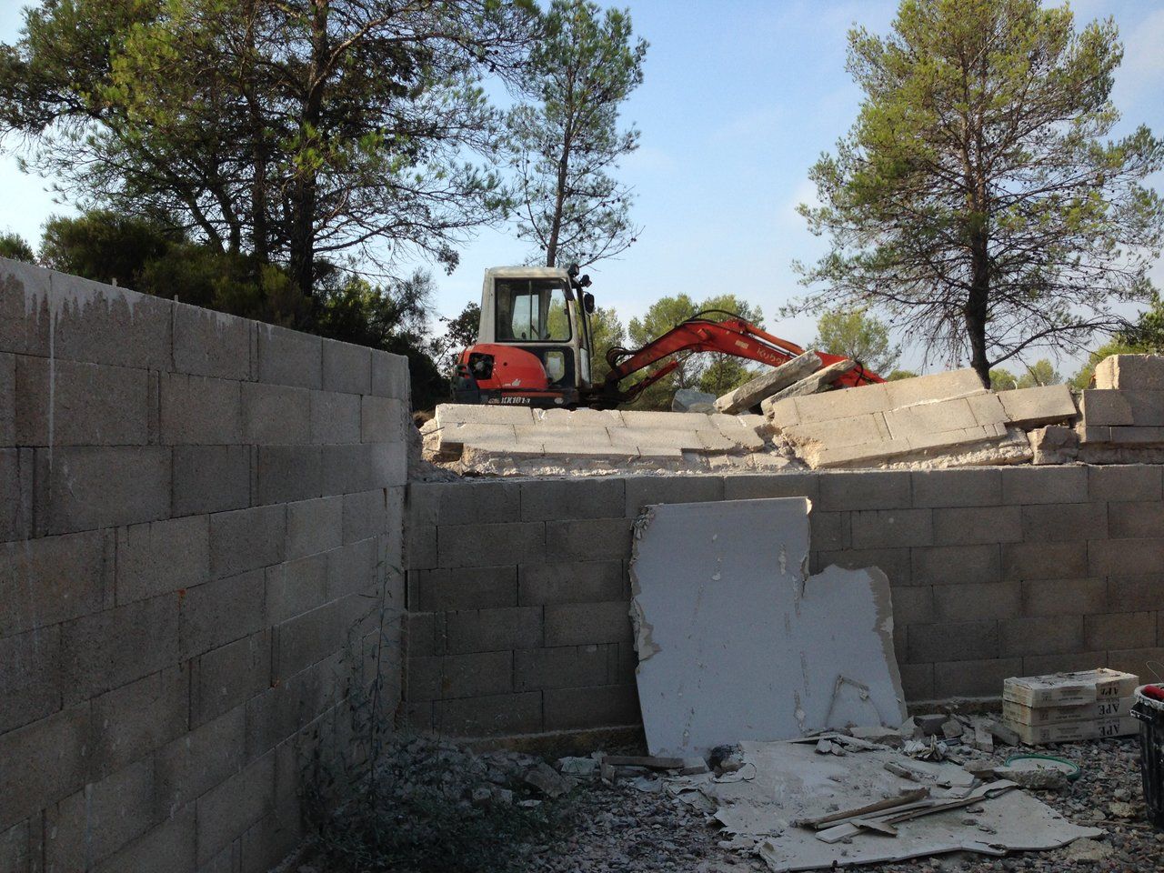 Mini-pelle sur un chantier, entre des murs en parpaings